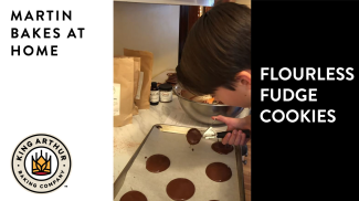 Arlo scooping flourless fudge cookie batter onto baking sheet